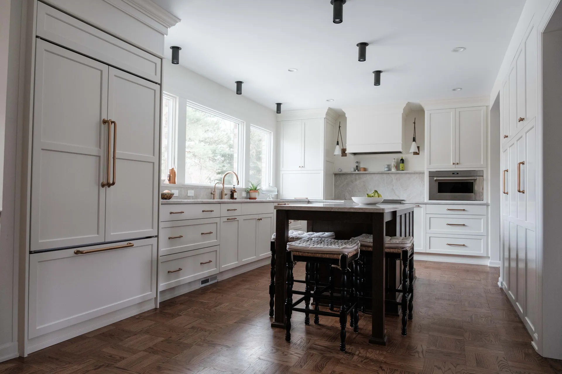 Custom two-tone kitchen remodel with cream shaker cabinetry, a dark wood island with stone top, brass hardware and herringbone wood floors, Greater Lansing