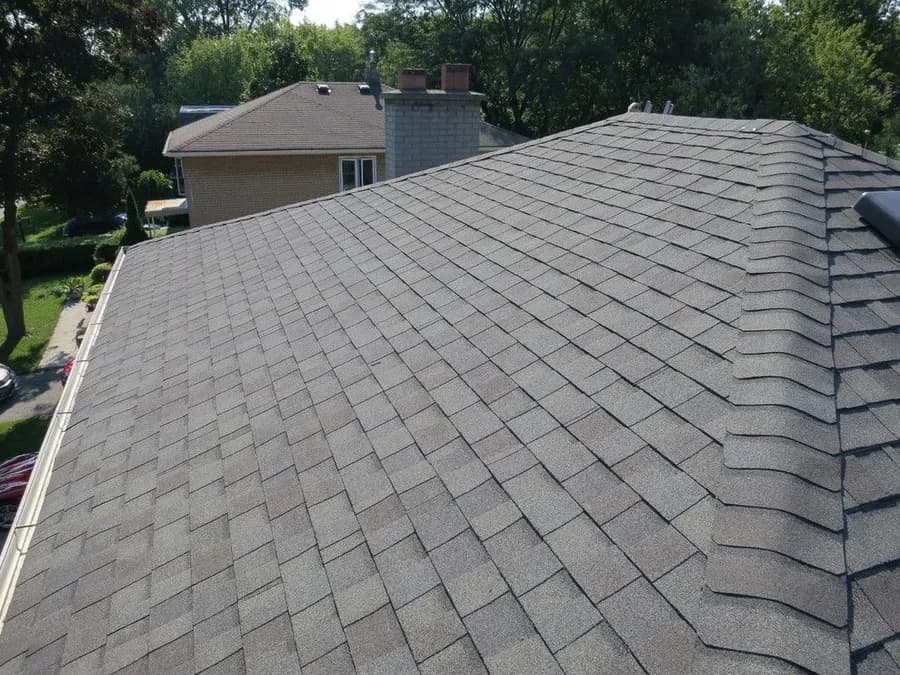 Newly installed architectural asphalt shingle roof, elevated view with ridge-cap detail