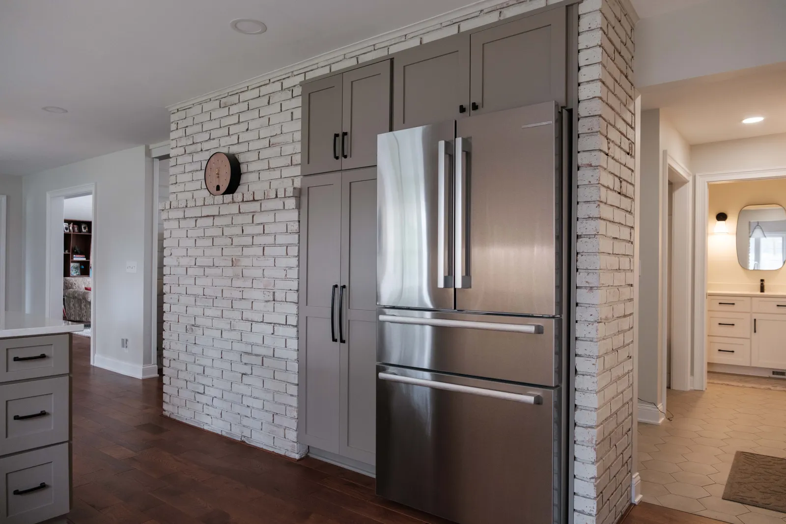 Finished kitchen with a stainless refrigerator set into a whitewashed brick niche where an old indoor brick grill once stood